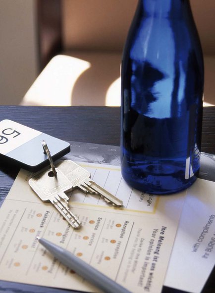 Room key with a bottle of water and questionnaires on a table.